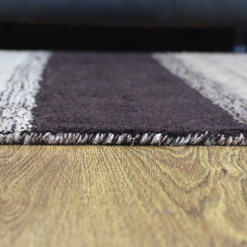 Hand-knotted area rug corner detail with fringed edge on dark gray stripe