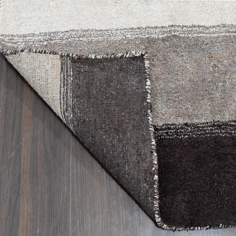 Hand-knotted area rug with striped face, bound edge, and fringed corner detailing
