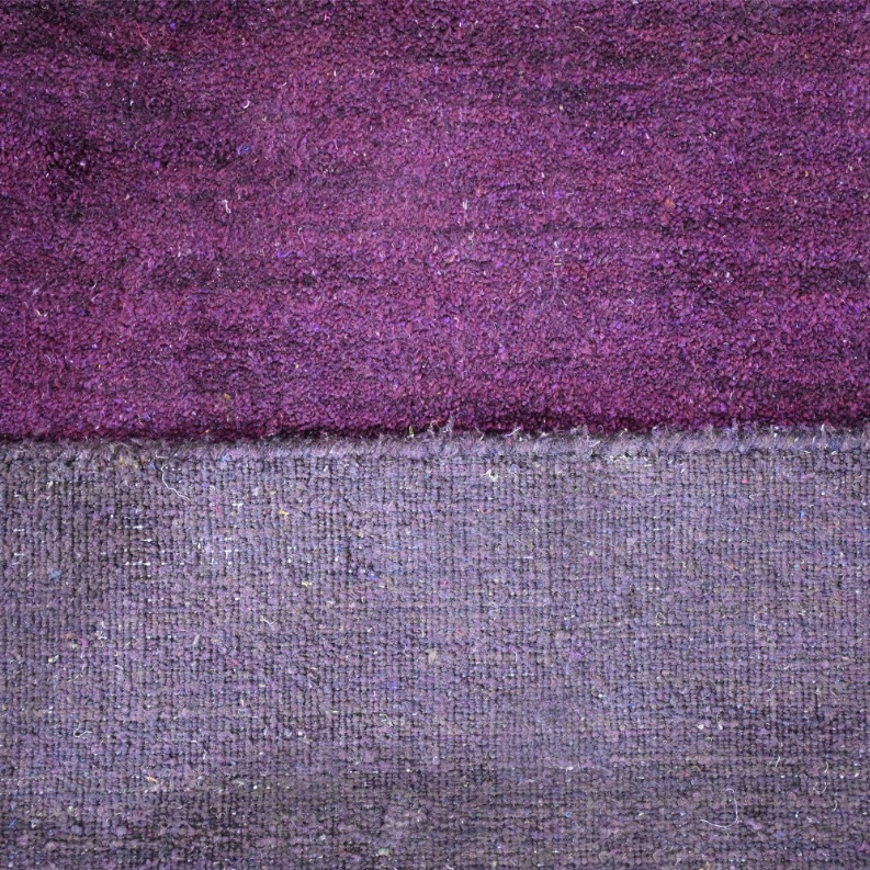 Border close-up: purple rug top with gray backing and tightly woven texture
