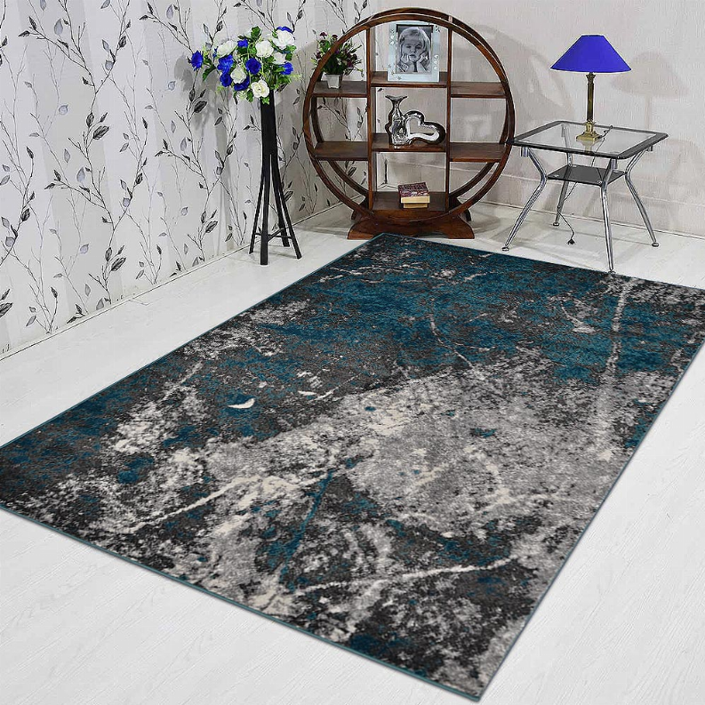 Abstract area rug with teal and gray distressed pattern in a room setting
