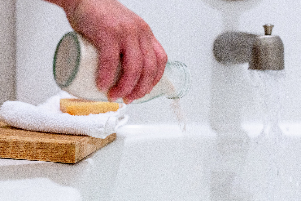 Coconut milk bath soak crystals poured into a white bathtub with folded towel