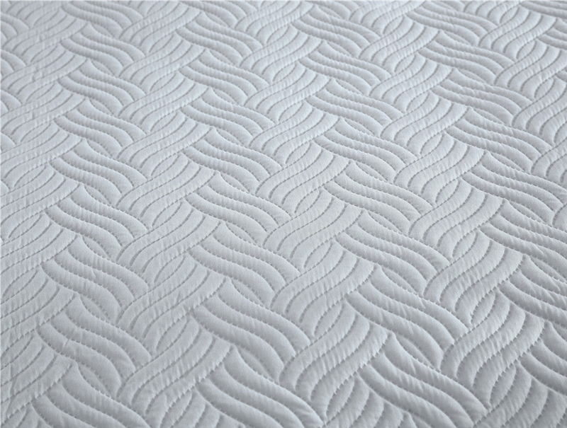 Gray quilted bedding close-up with wavy chevron stitch texture