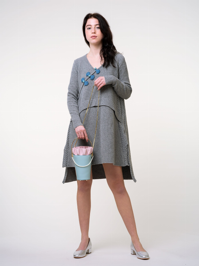 Light blue bucket bag with white ruffled top, gold chain shoulder strap and pull detail