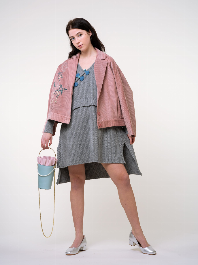 Light blue bucket bag with pink ruffle rim and gold chain strap, carried at waist