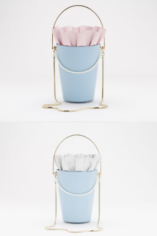 Light blue bucket bag with pink ruffle rim, gold chain handles and long shoulder strap