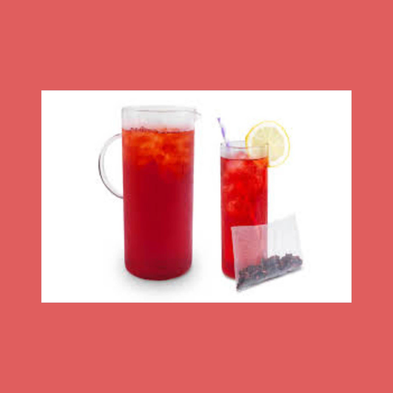 Glass and pitcher of red iced hibiscus tea with lemon slice