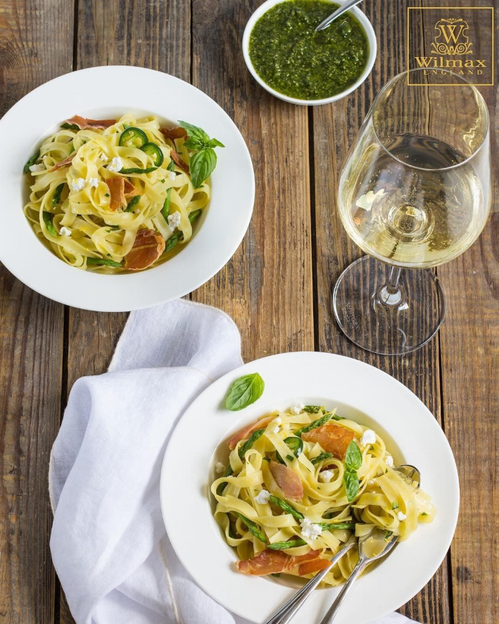 White deep plates with pasta and garnish on a rustic tabletop