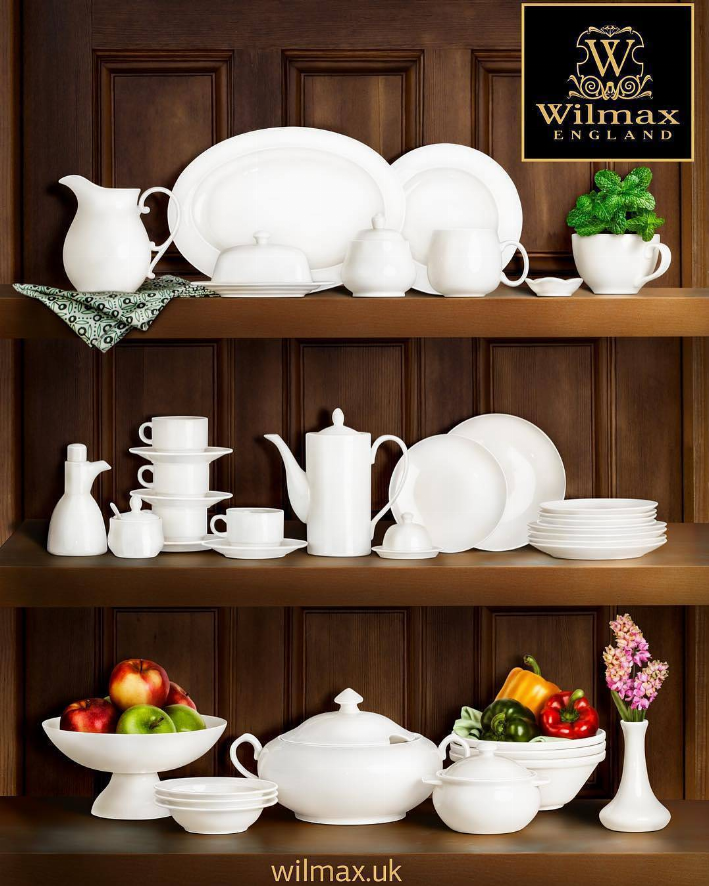 White deep plate set with other white dishware pieces on wooden shelves