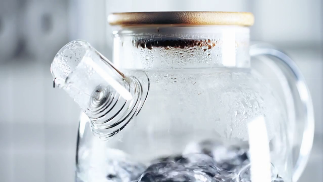 Close-up of clear glass spout and lid with condensation droplets