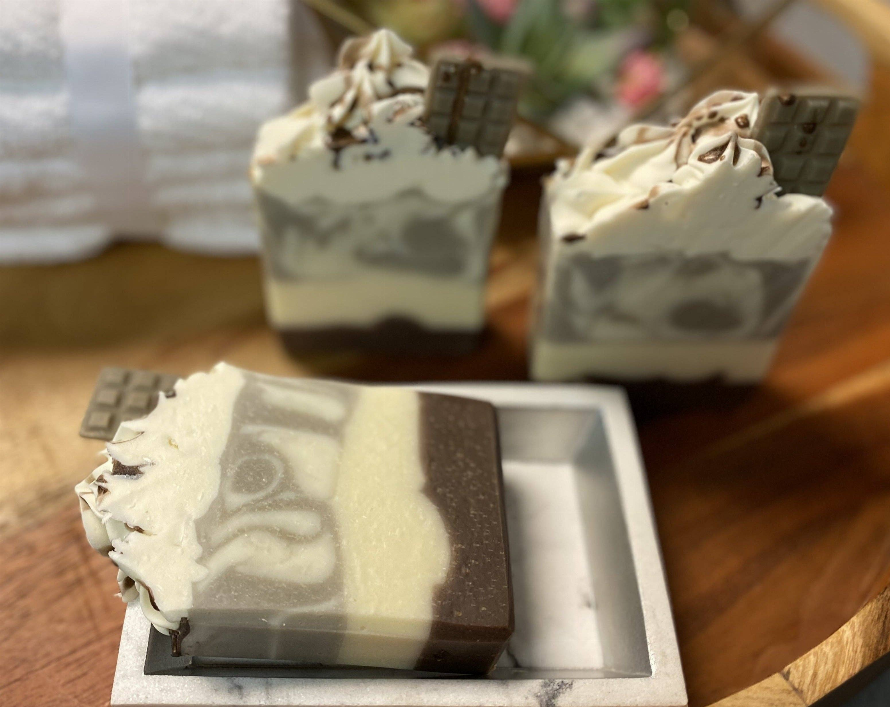 Chocolate and almond soap bar, creamy white with dark brown chocolate pieces, on tray