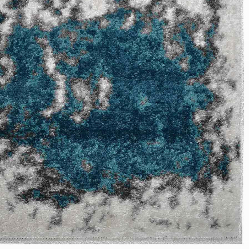 Abstract area rug close-up with deep teal medallion and mottled light gray border