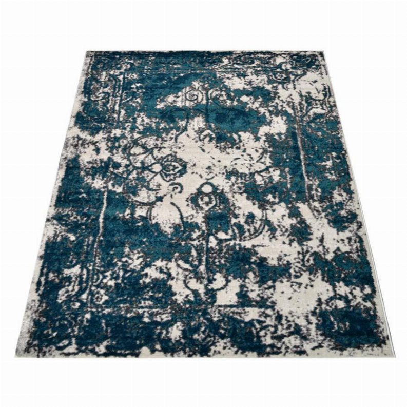 Abstract area rug featuring distressed teal blocks and off-white ornamental motifs