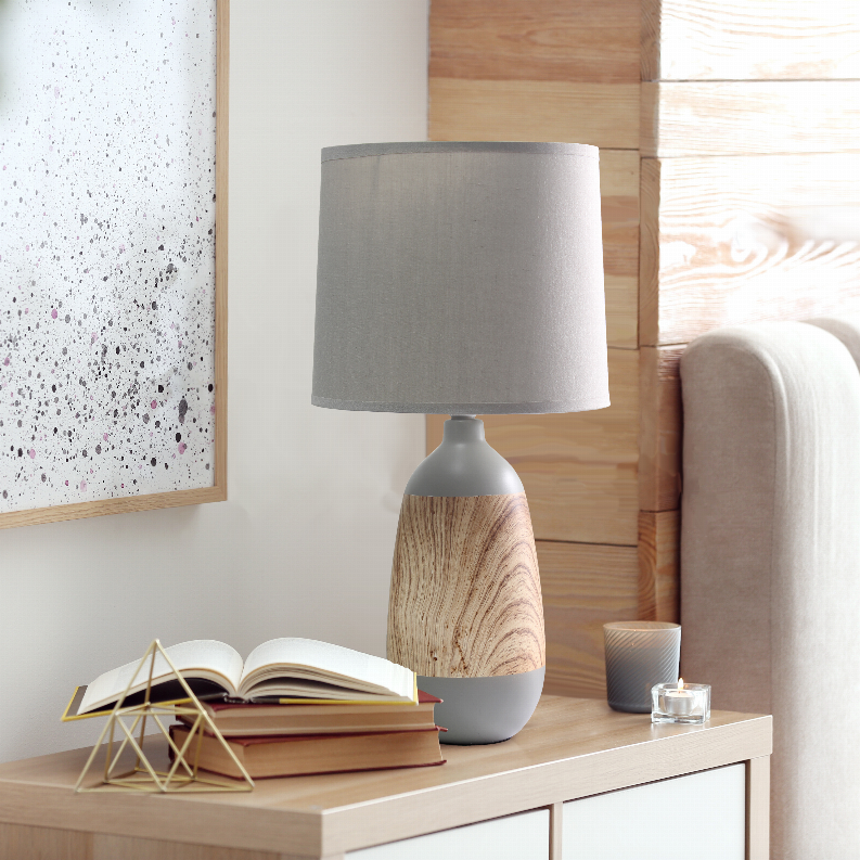 Gray drum-shade ceramic table lamp with light woodgrain base on side table