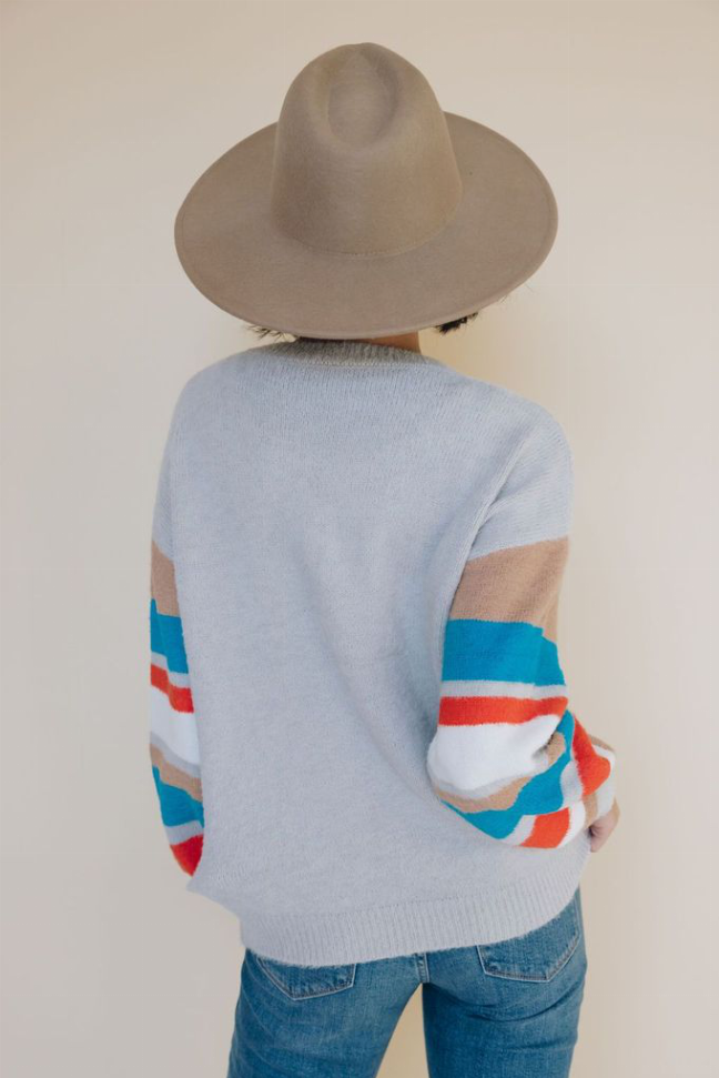 Light blue knit sweater with multicolor striped arm bands and ribbed cuffs