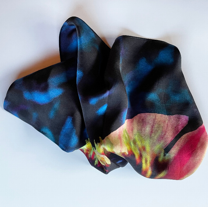 Square scarf laid flat with blue and pink abstract flower pattern on dark base