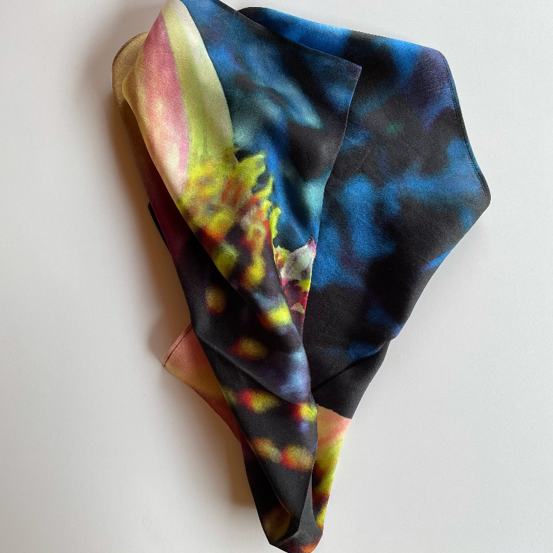 Square scarf folded with multicolor abstract flower print in blue, black, and pink