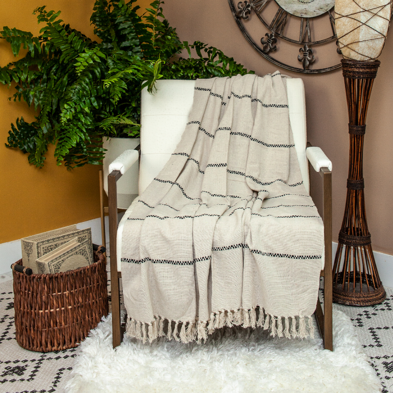 Beige woven throw blanket draped with dark check pattern and tassel fringe