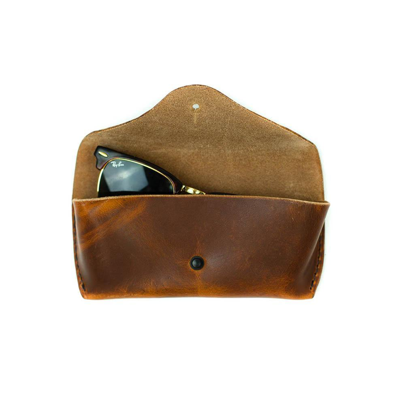 Tan and brown sunglasses case open with sunglasses inside and snap closure