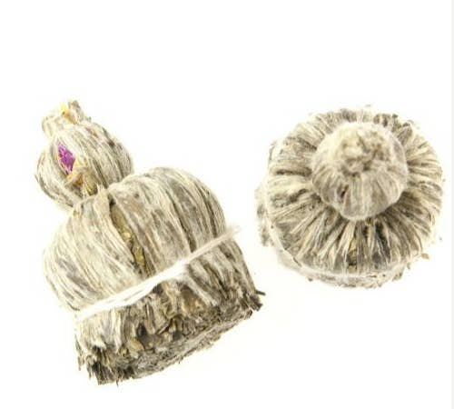 Blooming flower tea balls, two dried tea spheres with visible purple center