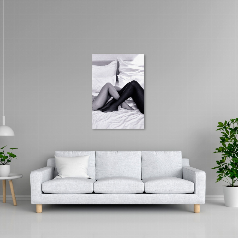 Glass wall art with black-and-white photo of legs on a bed