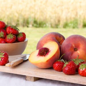 Strawberry peach white balsamic vinegar with peaches and strawberries on a wooden board