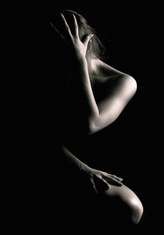 Monochrome female nude silhouette on black glass wall art, close-up pose