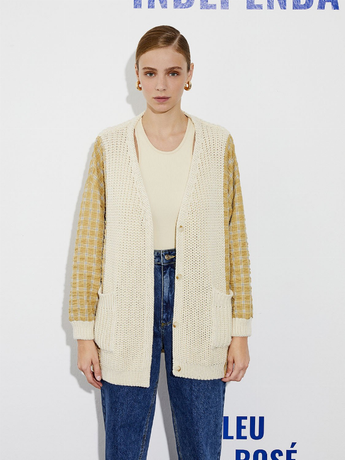 Cream knit cardigan featuring a textured front and yellow plaid sleeve panels