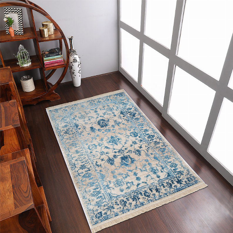 Blue and cream rectangular area rug with vintage floral medallion and fringe ends.