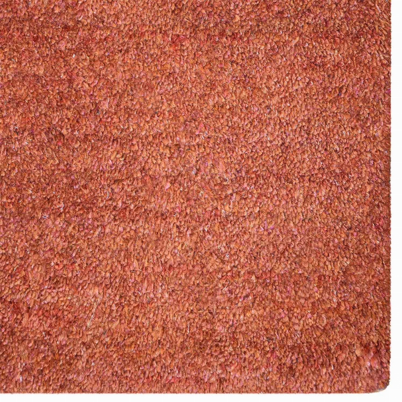Hand-knotted area rug close-up with textured orange-red pile