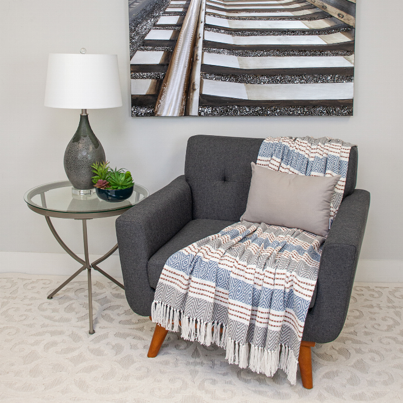 Natural solid lumbar pillow on dark gray chair with throw blanket in view