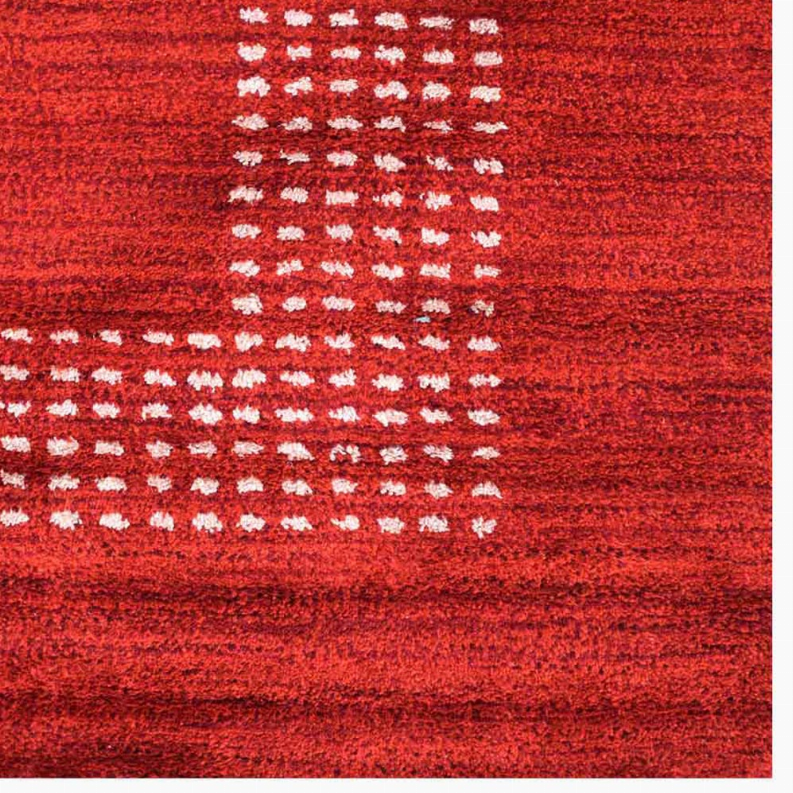 Close-up: red rug surface with cream diamond-dot pattern bands across the design.