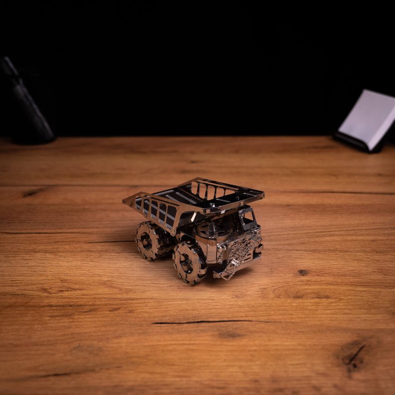 Metal mining truck model kit on wooden surface, compact view with tracks visible