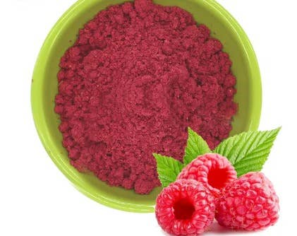 Freeze dried raspberry powder in green bowl with raspberries and leaf garnish