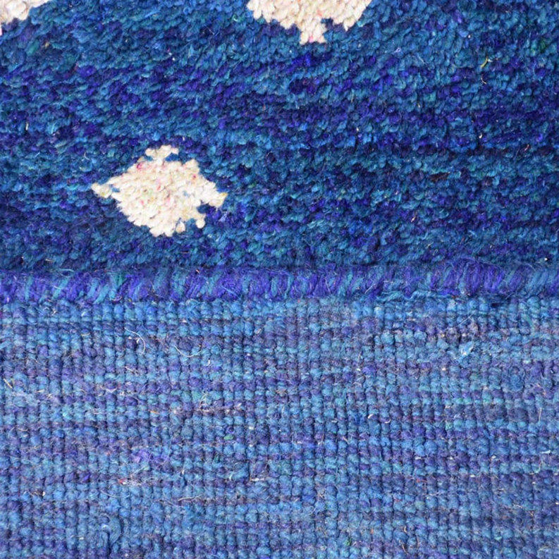 Blue rug close-up showing white diamond motifs and woven texture
