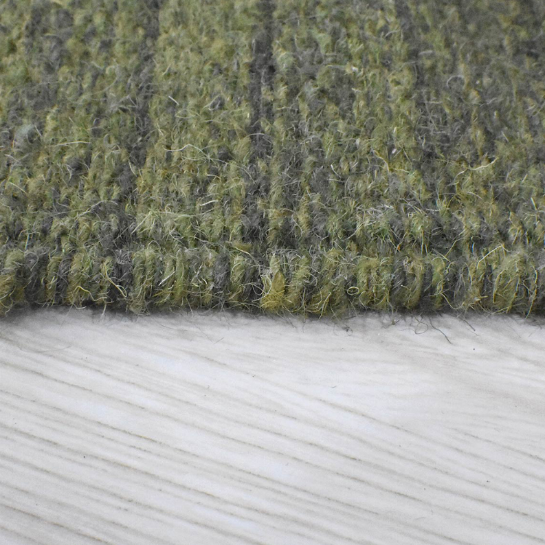 Olive green hand-woven wool kilim rug edge with short pile and white underside