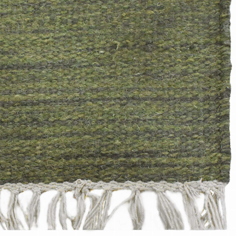 Hand-woven wool kilim rug in olive green with white fringe border detail