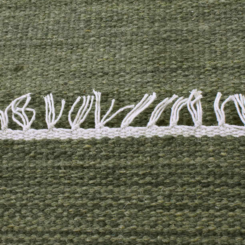 Olive green wool rug border with white fringe detail