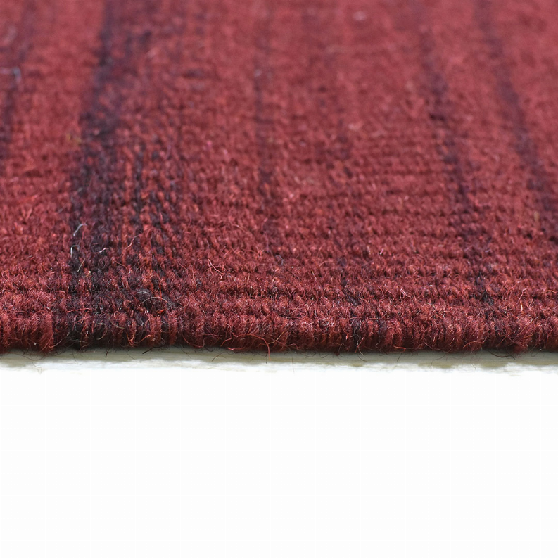 Side view of burgundy wool kilim rug showing dense pile and stitched edge