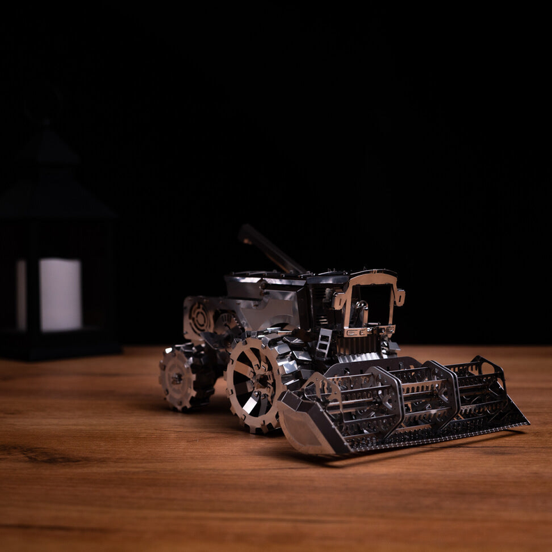 Metal harvester toy with tread wheels and front scoop, dark bronze and silver.