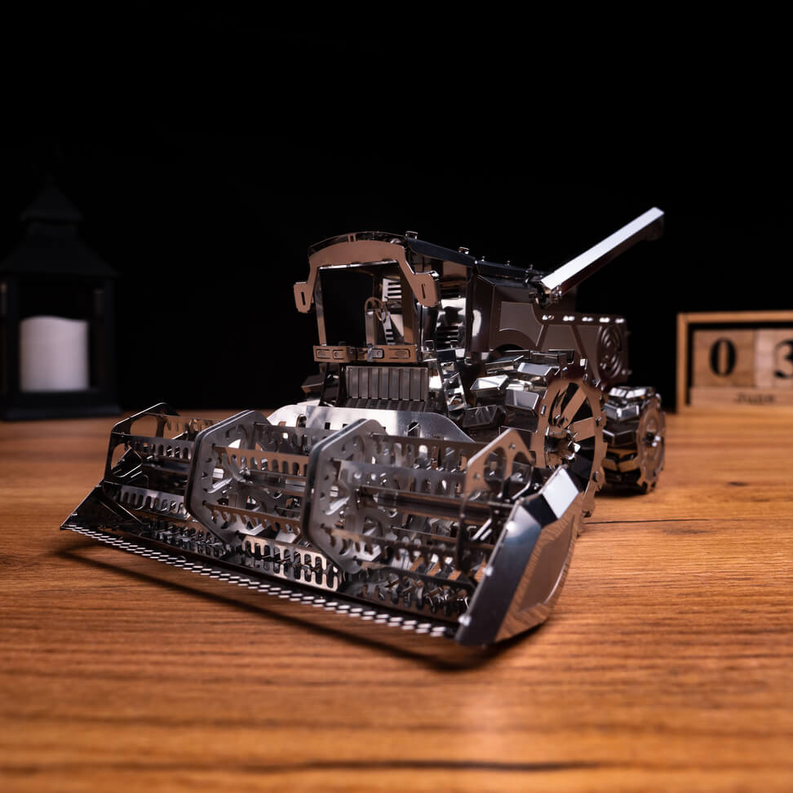Metal harvester toy angled view with raised arm and front scoop frame, bronze and silver.