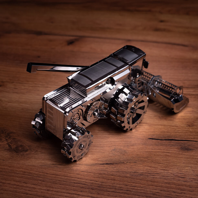 Metal harvester toy with long arm and wide front scoop, bronze and silver.