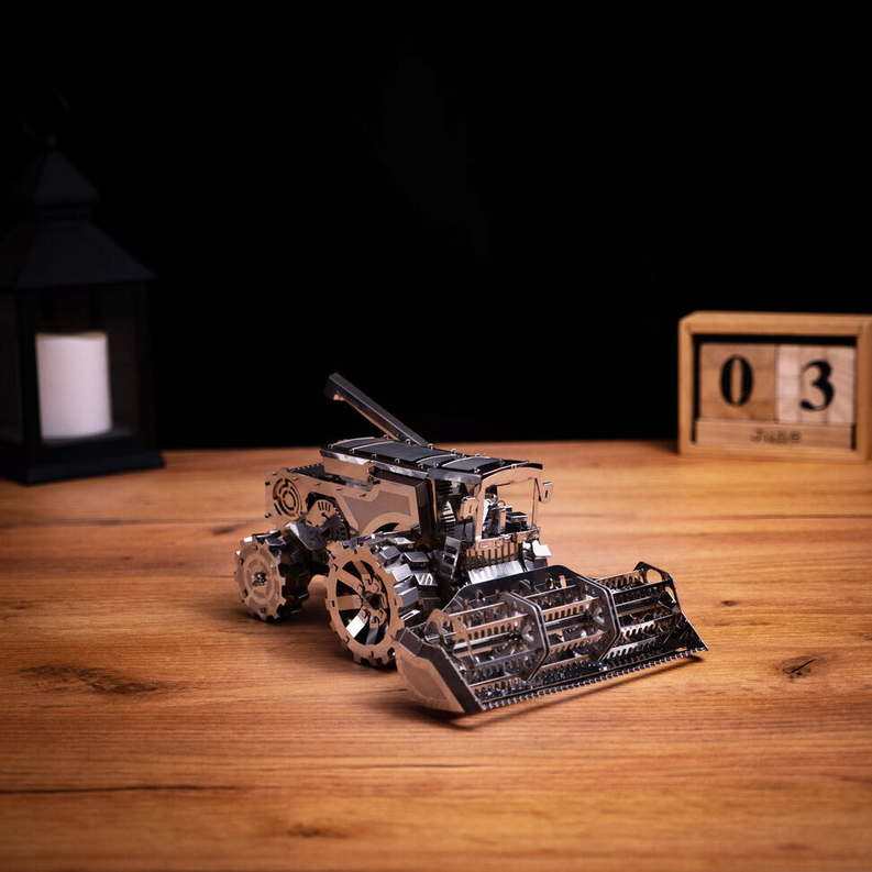 Metal harvester toy with rear body and front scoop, bronze and silver, side view.