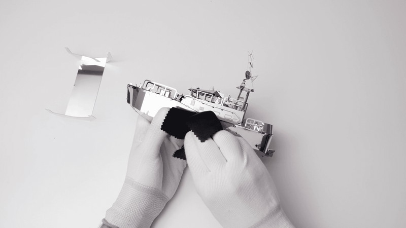 Boat model being fitted by gloved hands during assembly