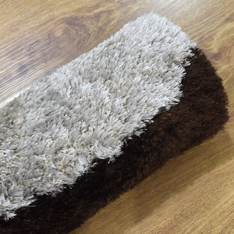 Shag rug with thick white pile over dark brown backing along rug edge