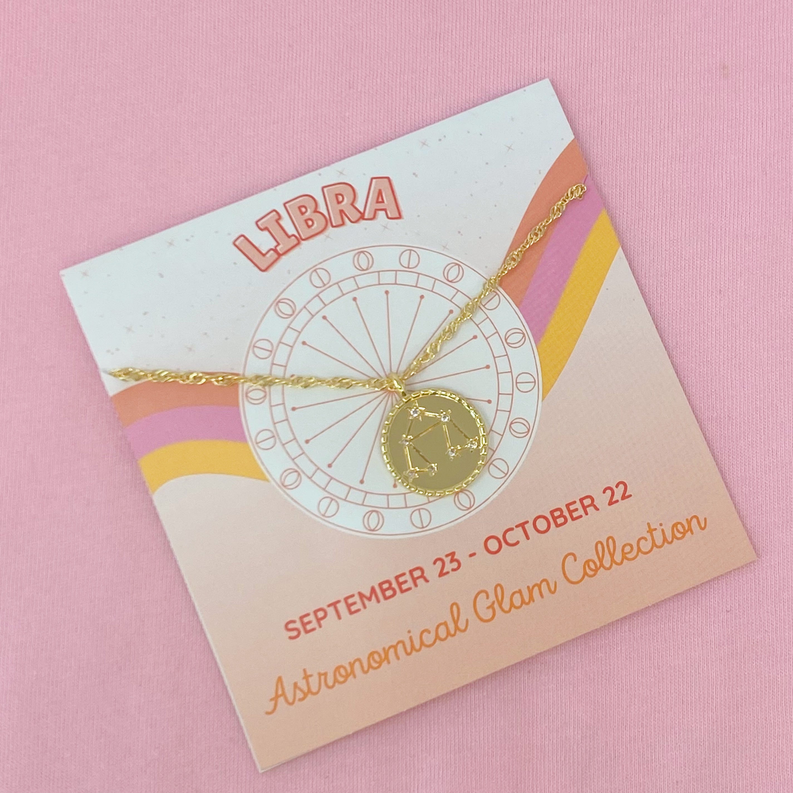Libra zodiac charm necklace on gold chain shown on boxed card