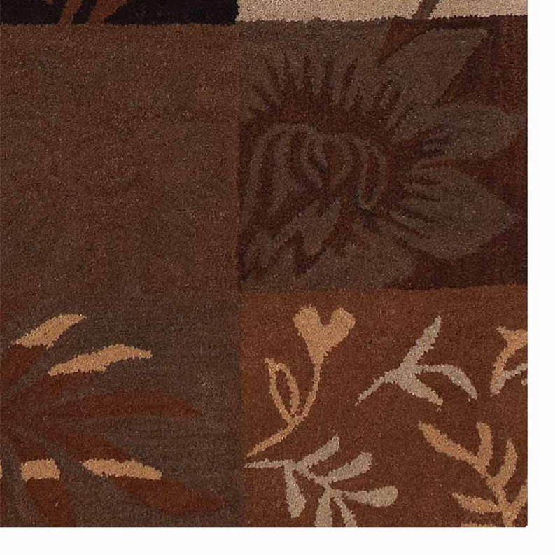 Close-up of floral leaf motif on brown patchwork area rug with tan pattern