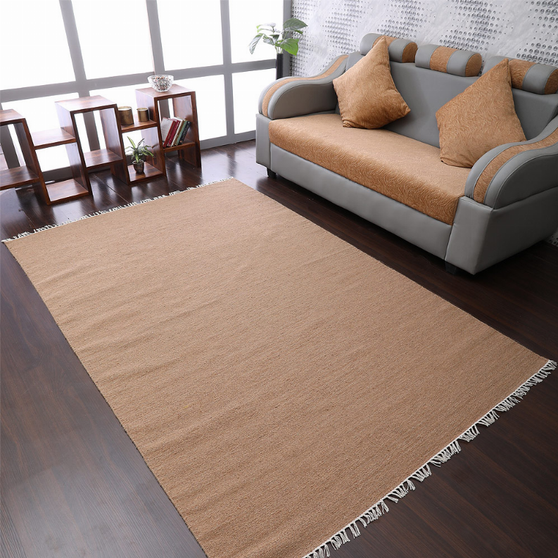 Tan solid flatweave Kilim wool area rug with white fringe, living room view