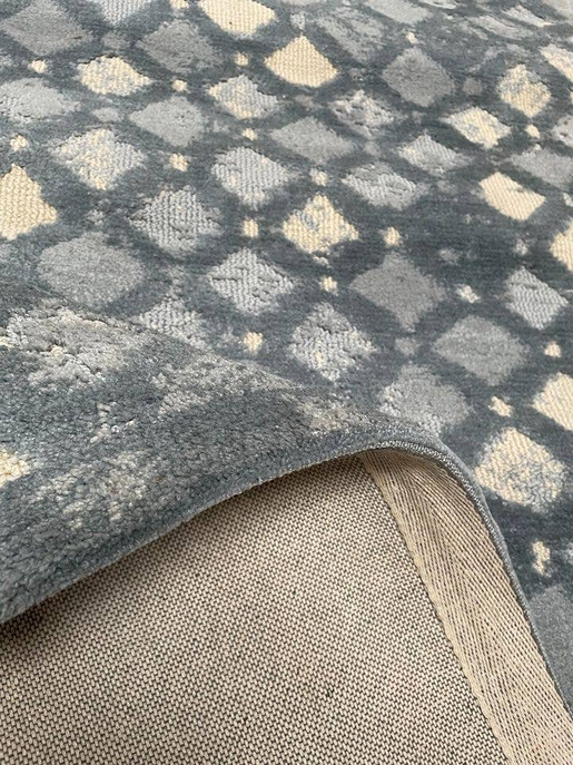 Geometric area rug edge with blue diamond pattern and visible backing