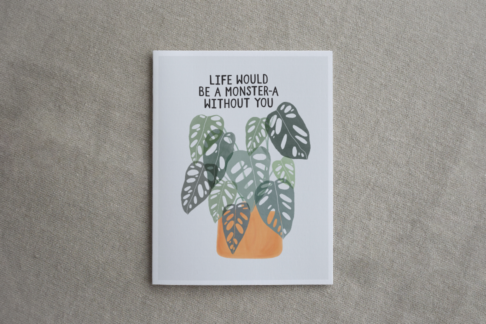 Framed monstera leaf wall art print with quote and white border on textured fabric.