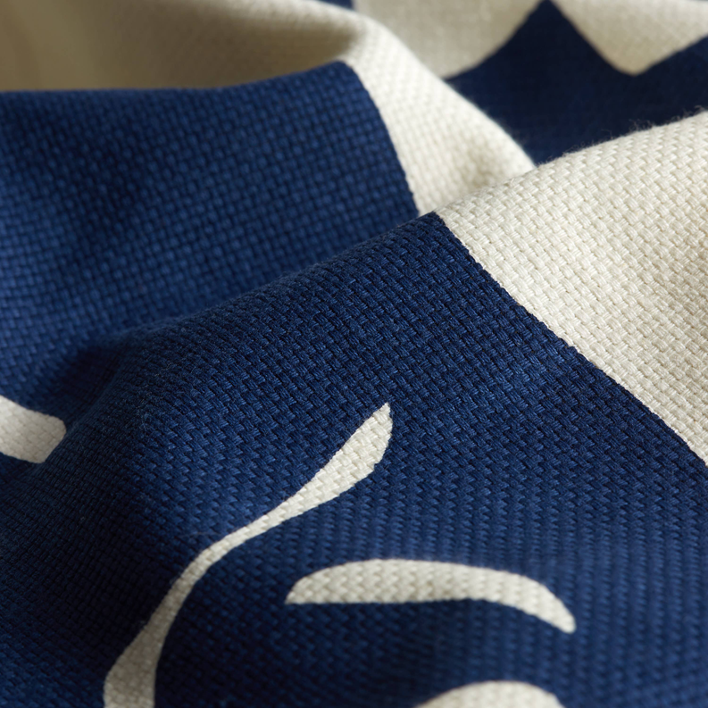 Close-up shower curtain fabric with navy parrot motif printed on cream woven textile.